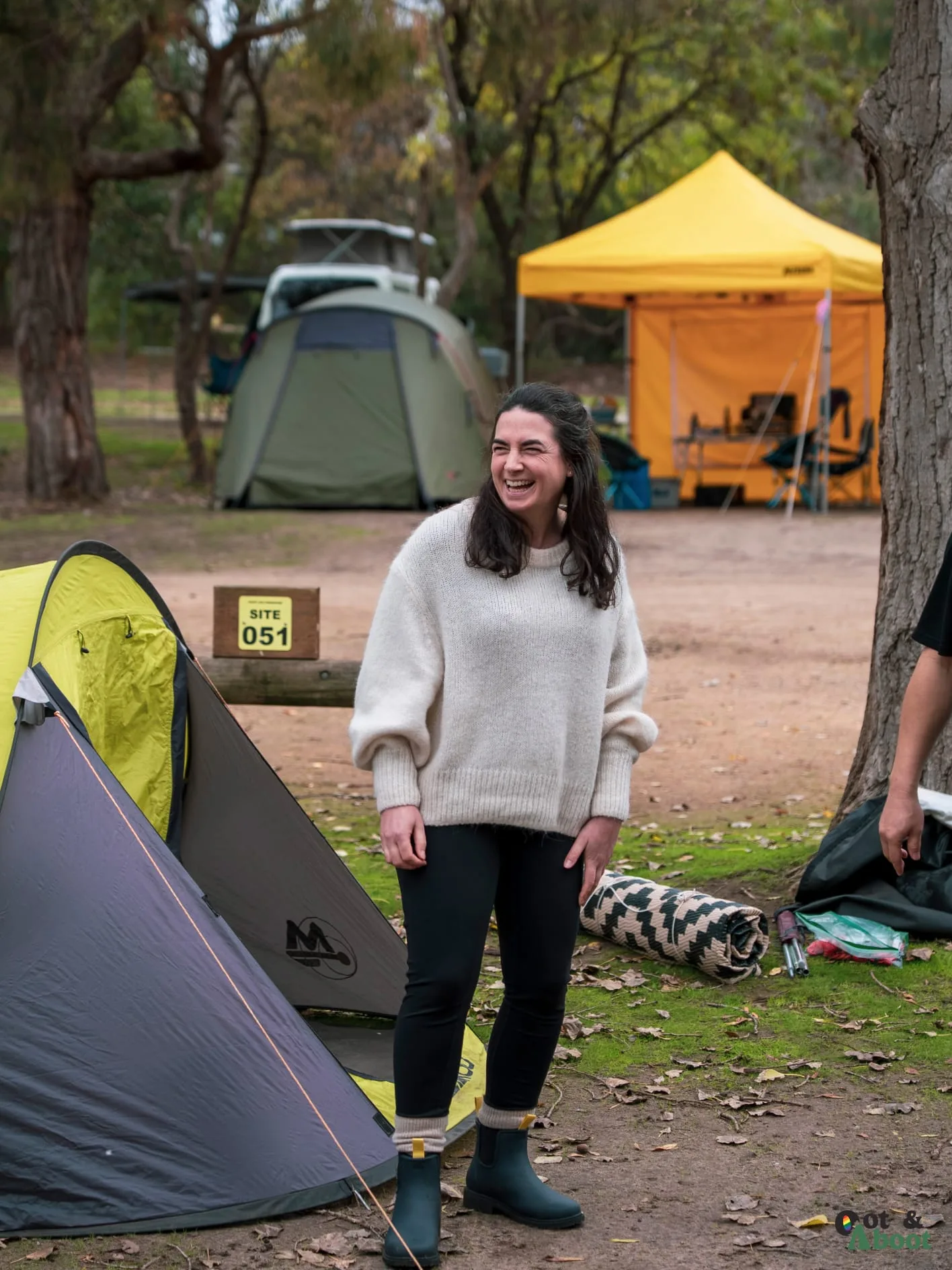 A camper smiling next to a tent